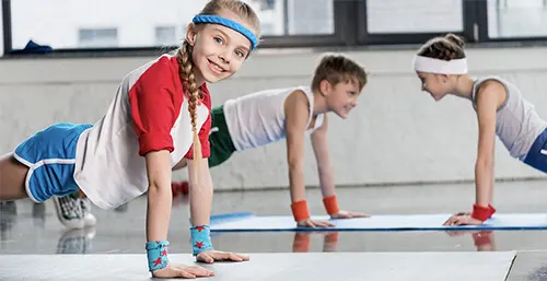 Ćwiczenia dla dzieci - jakie będą najlepsze dla dzieci w wieku szkolnym? Dzieci ćwiczą w sali gimnastycznej na lekcji W-F.